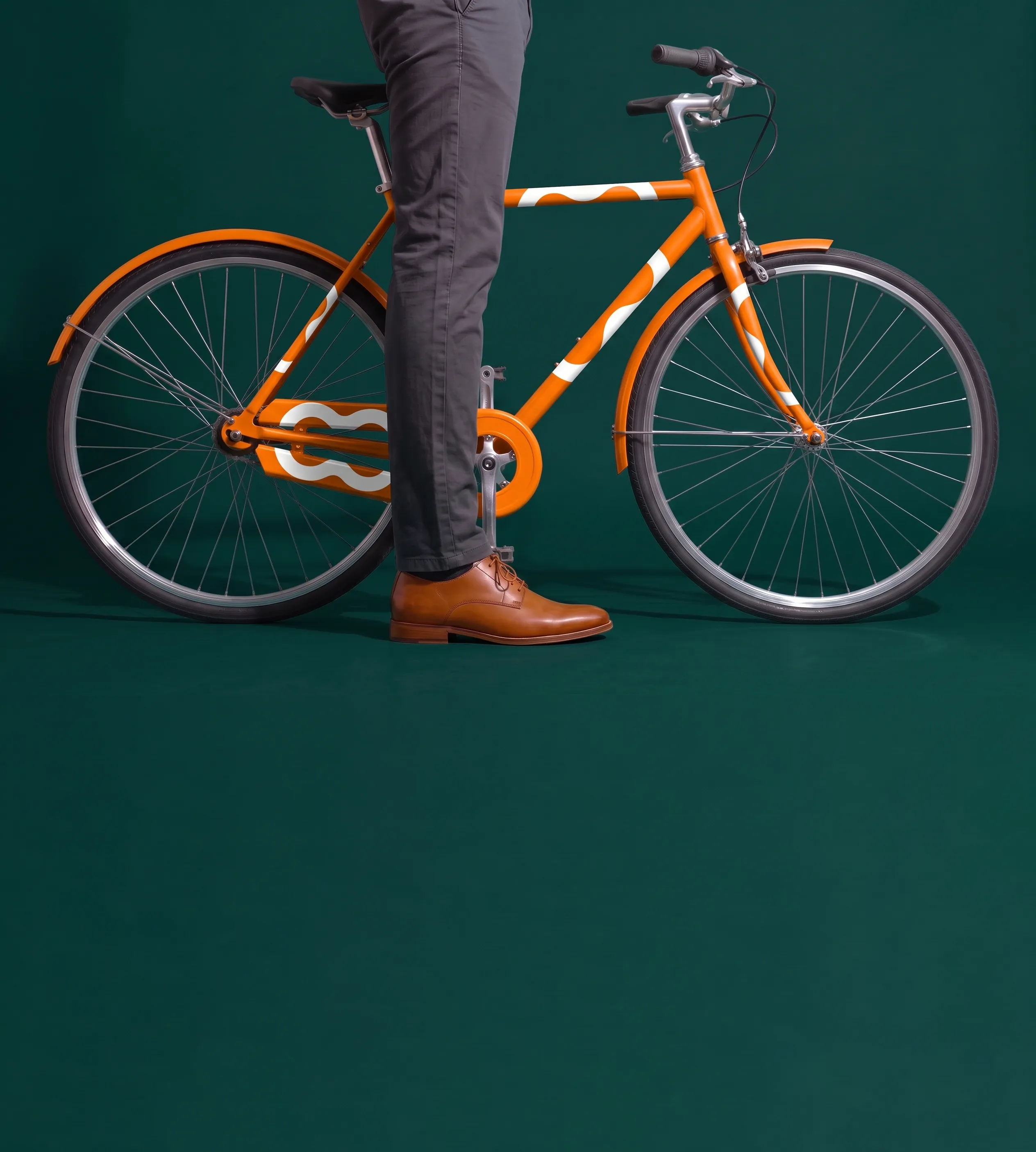 Vélo orange Monizze devant un fond vert foncé