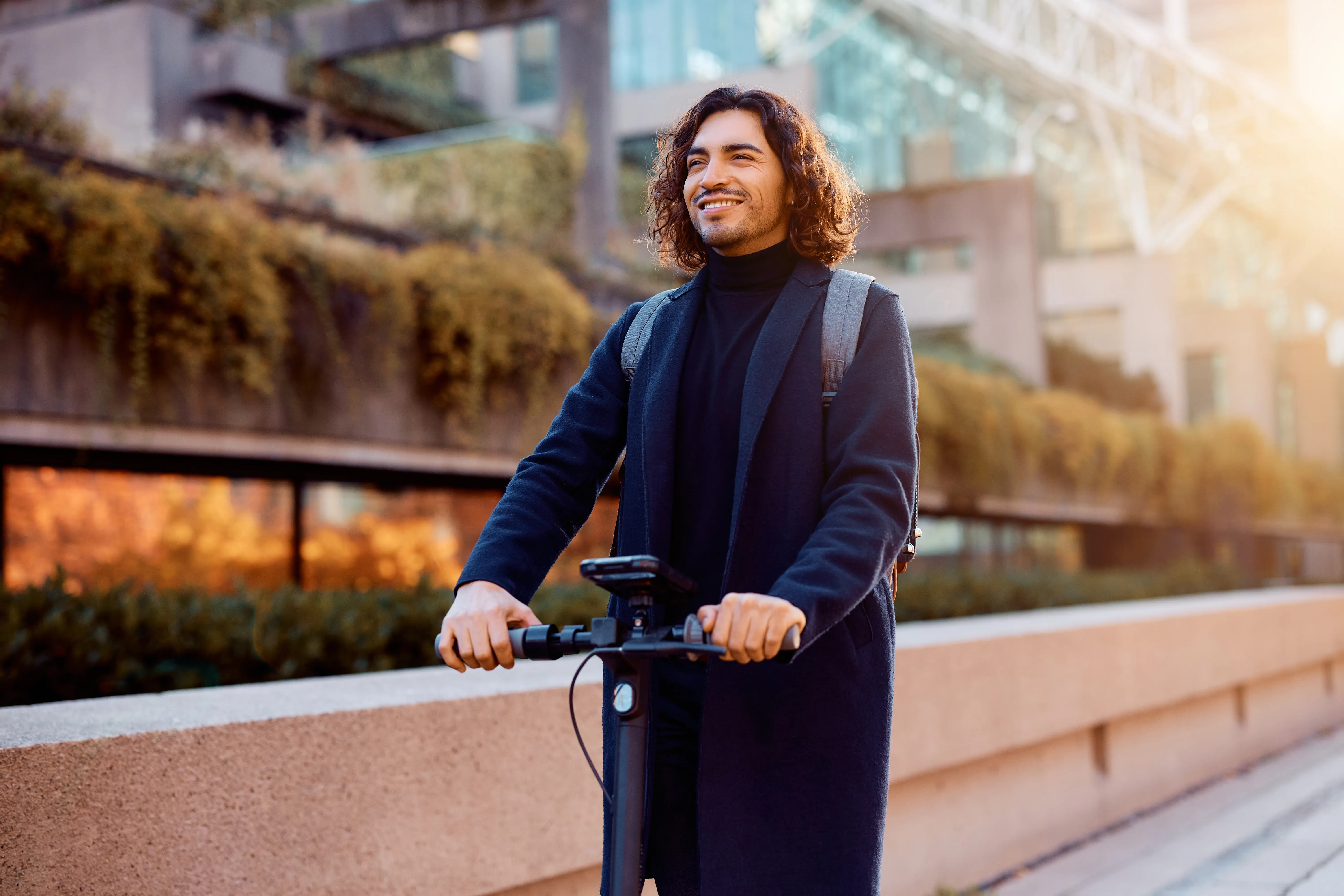 Collaborateur souriant en trottinette électrique en ville