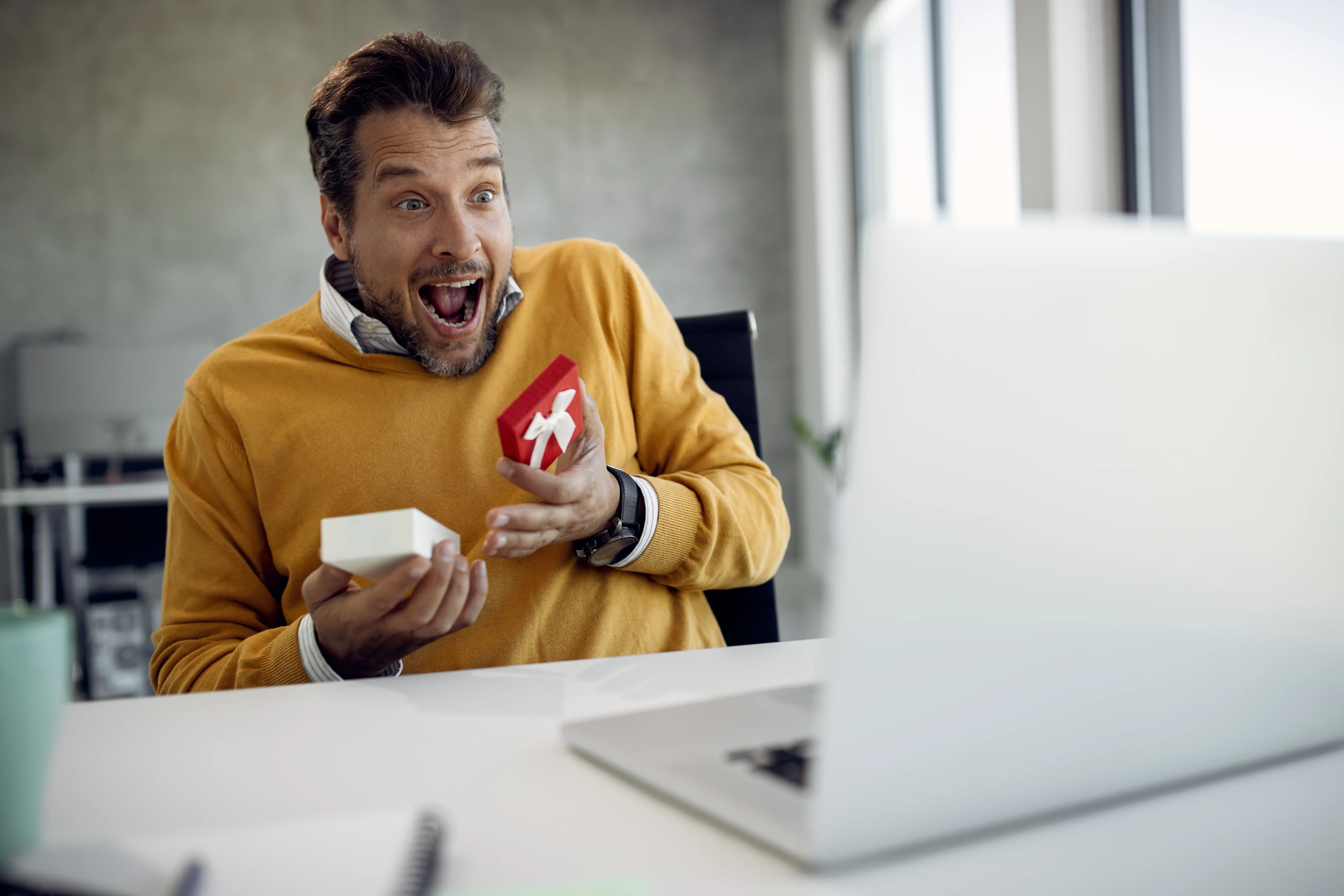 Surprised employee opening a corporate gift voucher at the office