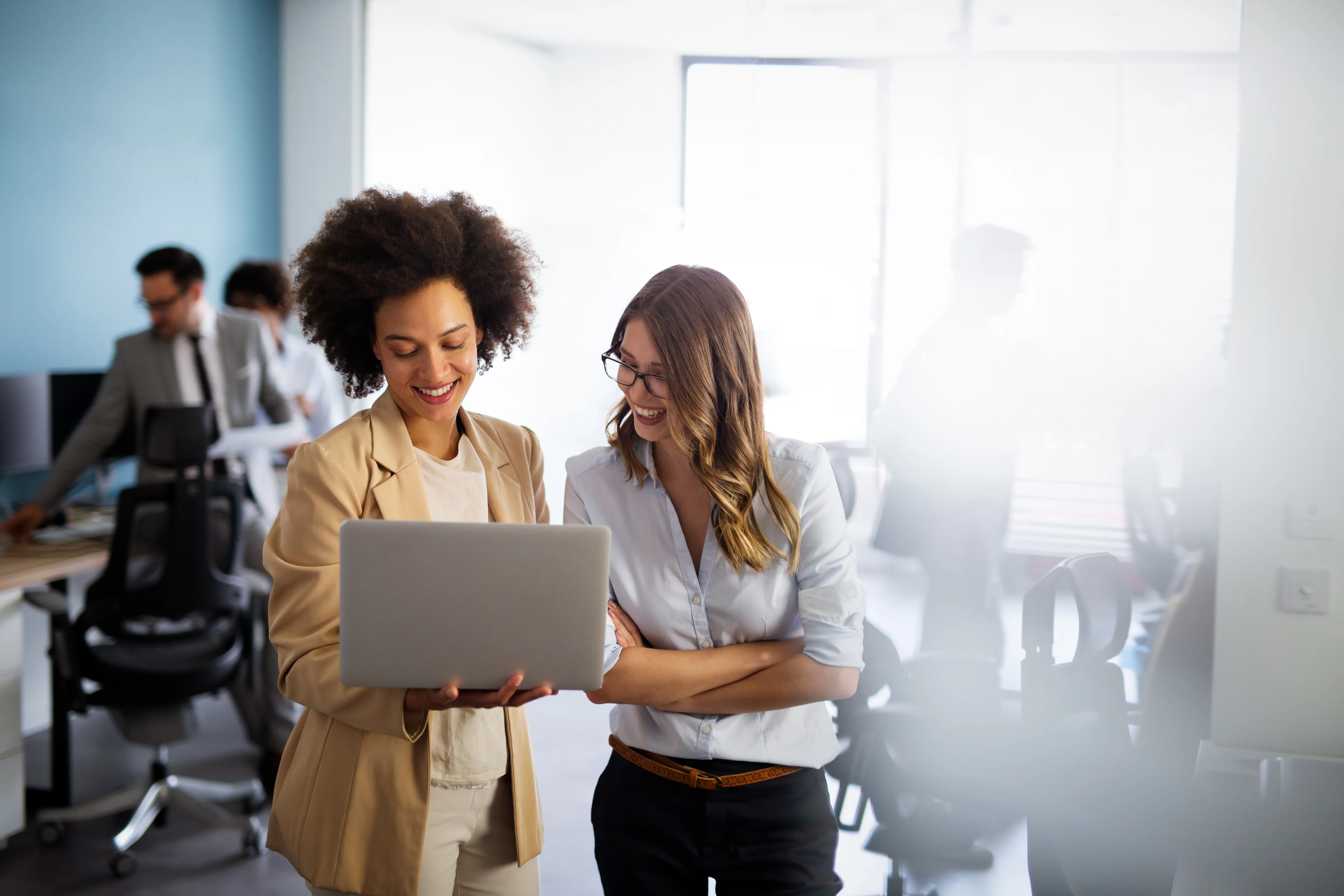Deux collaboratrices souriantes devant un ordinateur portable